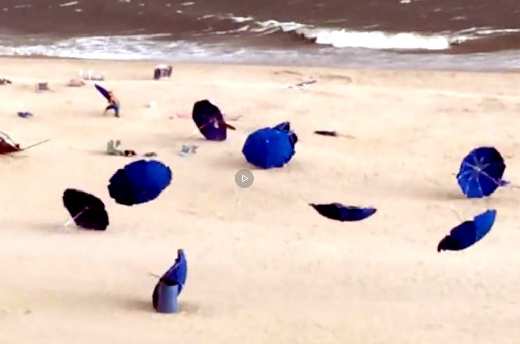 A group of people on the beach with umbrellas.